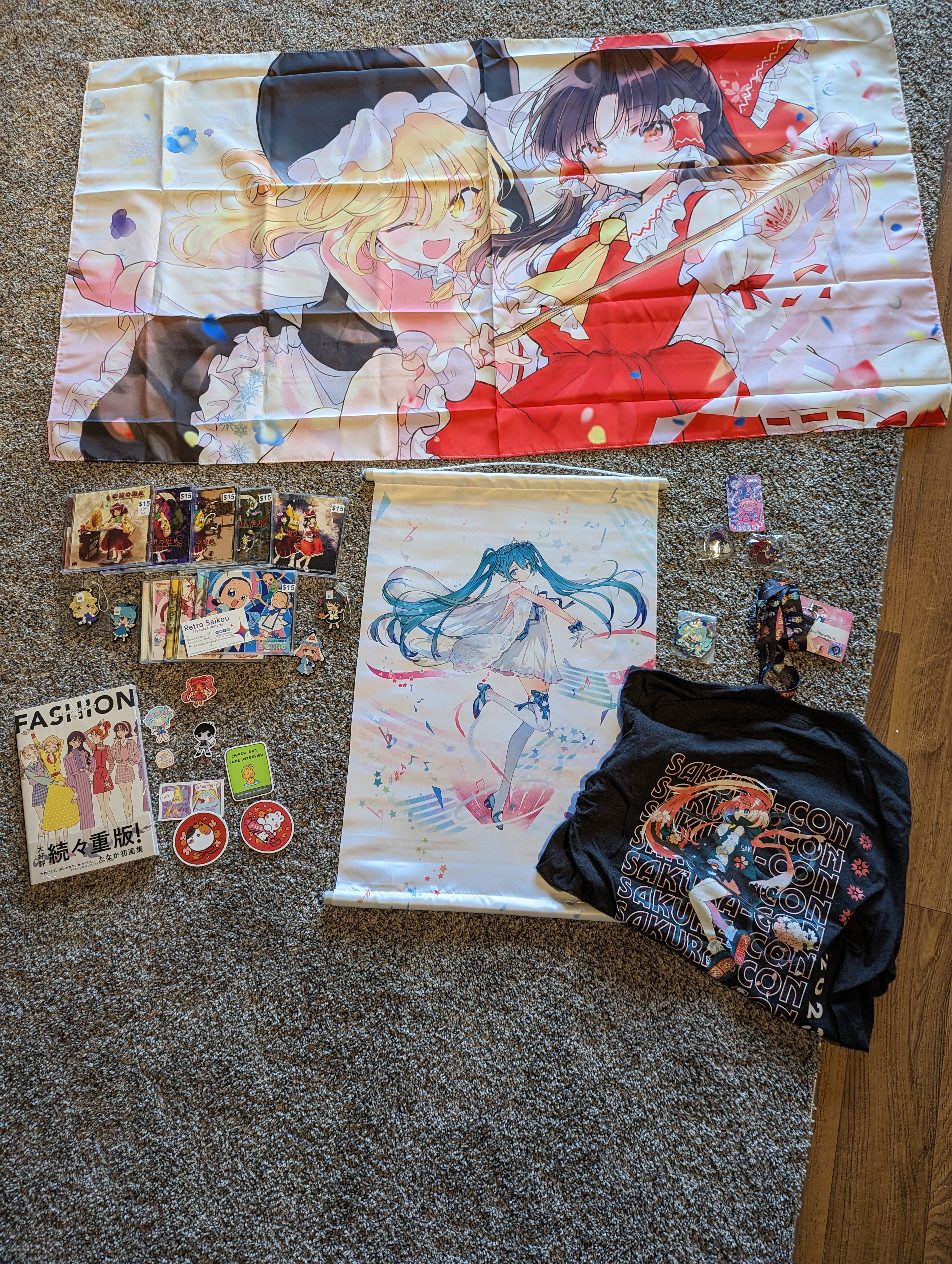 A Touhou banner, Miku wall scroll, assorted stickers and pins, 5 Touhou CD’s and 3
Ojamajo Doremi CD’s, a fashion artbook, and a Sakruacon
TShirt