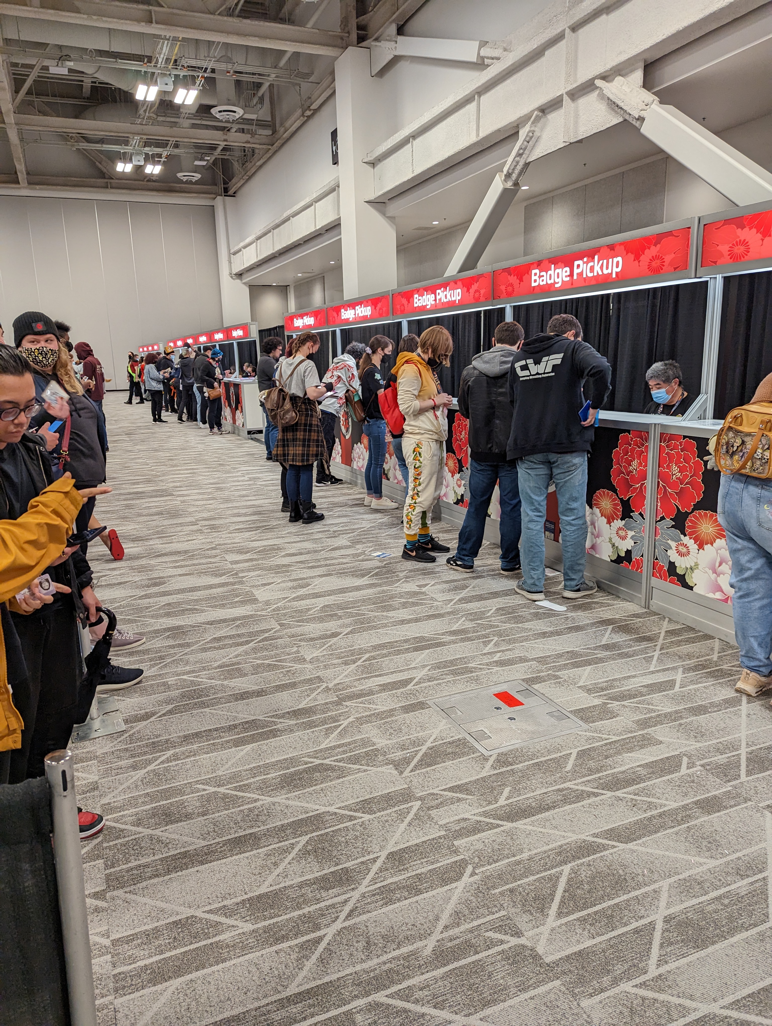 Picture of twelve badge pickup booths, all serving
people